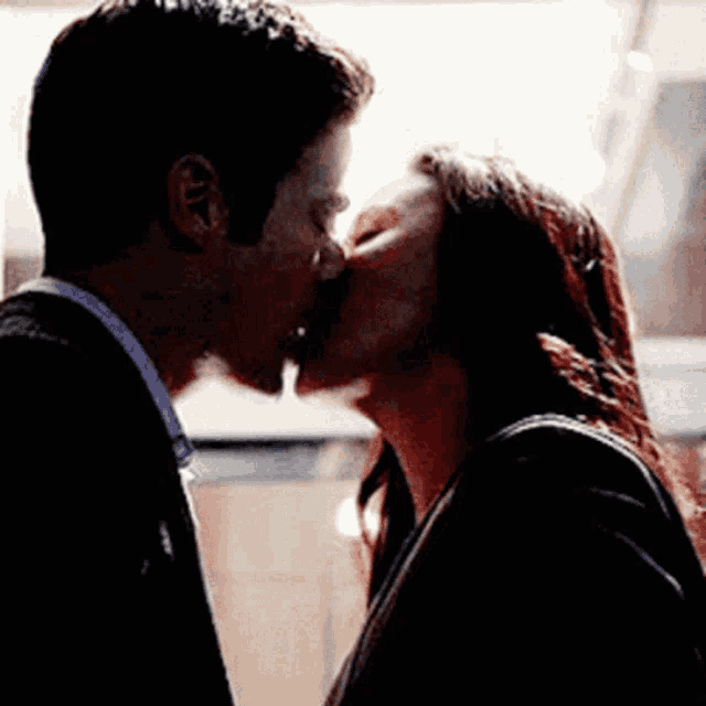 a man and a woman are kissing in a dark room