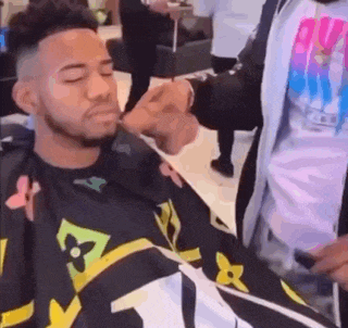 a man is getting his hair cut by a barber in a salon .