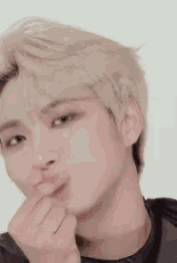 a close up of a young man making a heart shape with his finger .