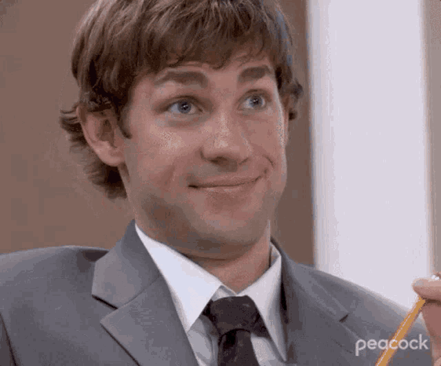 a man in a suit and tie is holding a yellow pencil .