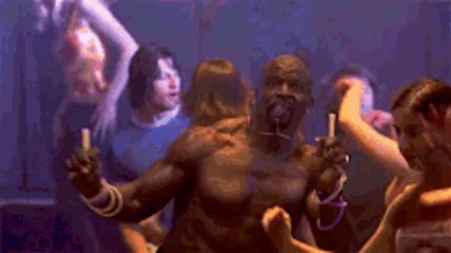a group of people are dancing in a dark room while a man holds a lighter in his hand .