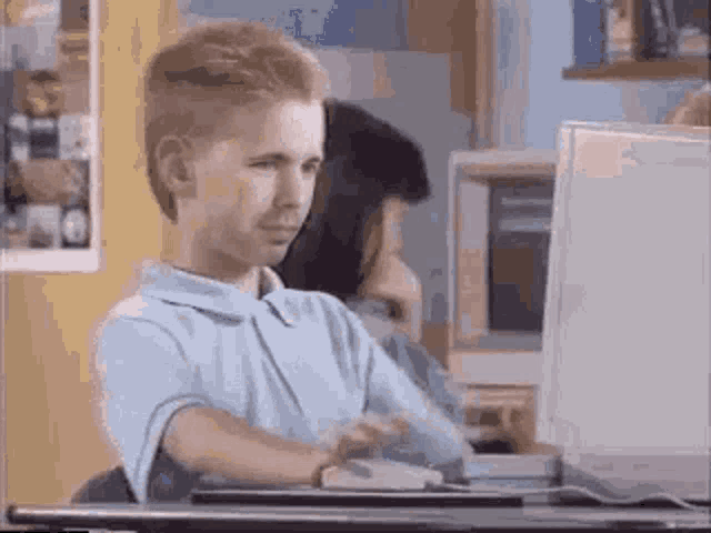 a young boy is sitting at a desk using a computer .