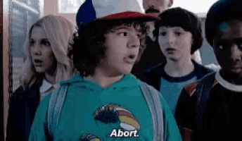a group of people are standing in a room and one of them is wearing a blue shirt that says abort .