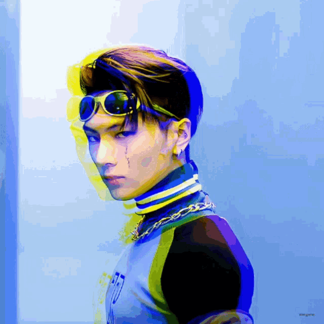 a man wearing sunglasses and a headband with the letter t on it is standing in front of a blue wall