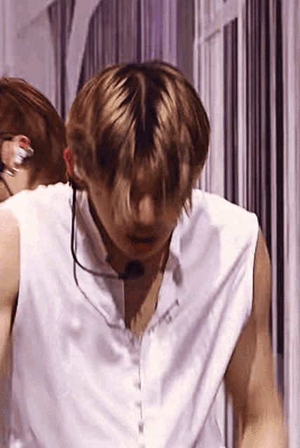 a man wearing a white sleeveless shirt and a microphone around his neck