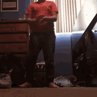 a man in a red shirt is standing in a room