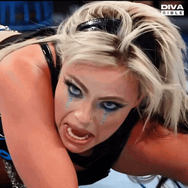 a blonde woman with blue eyes is making a funny face in front of a diva bible sign