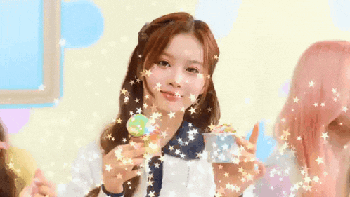 a girl is holding a lollipop in her hand with stars coming out of her face .