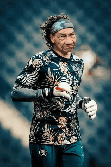a soccer goalie wearing a floral jersey and gloves is making a funny face .
