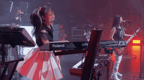 a woman is playing a roland keyboard while another woman plays a guitar