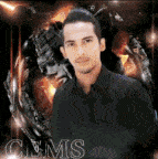 a man in a black shirt is posing for a picture in front of a fire .