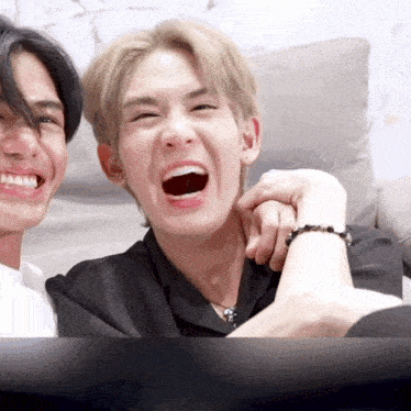 two young men are laughing together and one has a bracelet on his wrist
