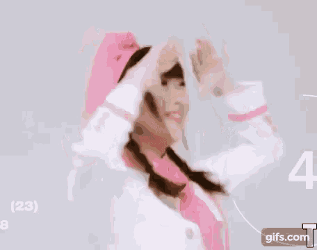 a girl in a pink hat and scarf is giving a peace sign .