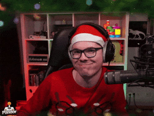 a man wearing headphones and a santa hat is sitting in front of a microphone with a pandor logo behind him