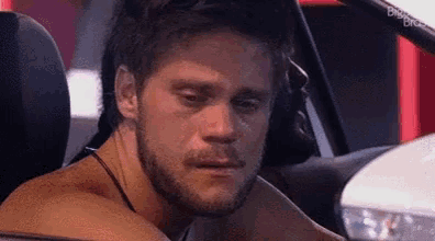 a man with a beard is sitting in the back seat of a car with his eyes closed .