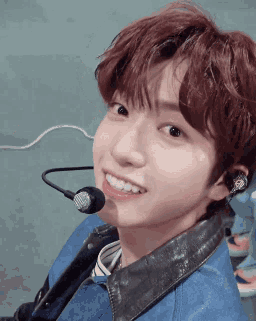a young man with a microphone around his neck smiles