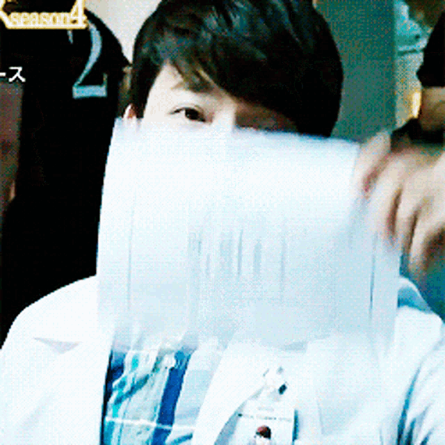 a person covering their face with a piece of paper with the number 2 on it