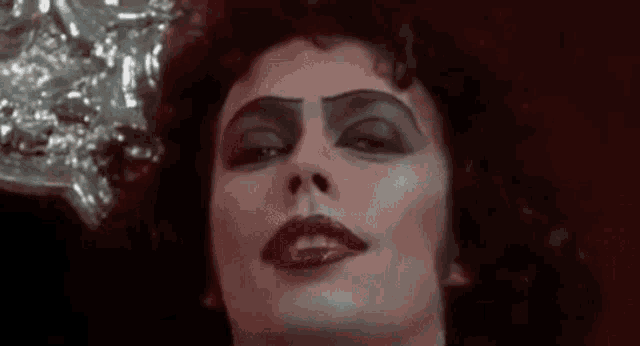 a close up of a woman 's face with red lipstick and black eyebrows .