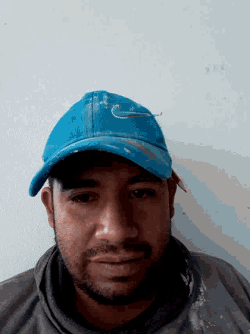 a man wearing a blue nike hat looks down at the camera