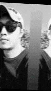 a black and white photo of a man wearing sunglasses and a baseball cap .