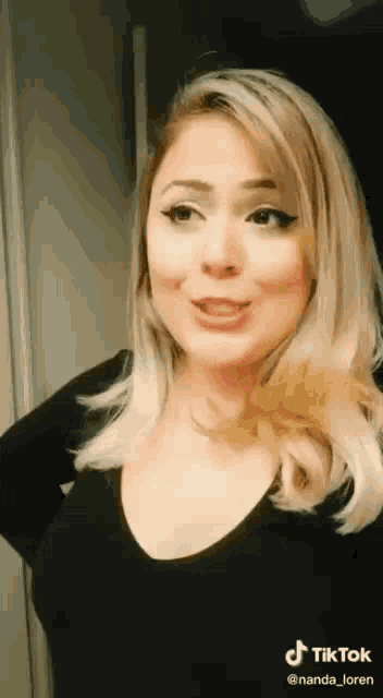 a woman with blonde hair is standing in front of a mirror .
