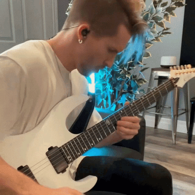 a man is playing a white electric guitar with a yamaha logo on the neck
