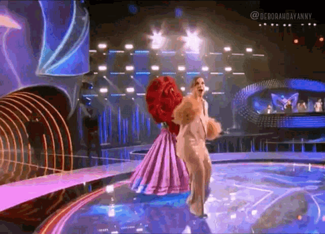 a woman in a purple dress is dancing on a stage in front of a crowd .