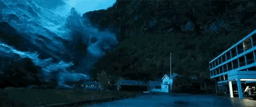 a large tsunami is coming down a mountain and destroying a building .