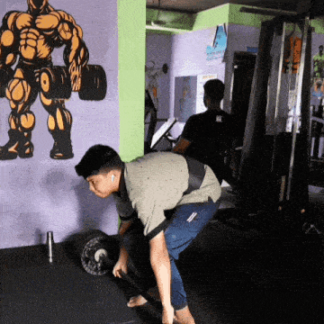 a man lifting a barbell in a gym with a picture of a muscular man on the wall