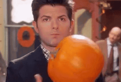 a man in a suit is holding an orange balloon in his hand .