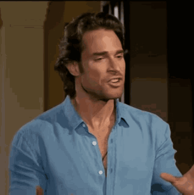 a man in a blue shirt is making a funny face while talking to someone .
