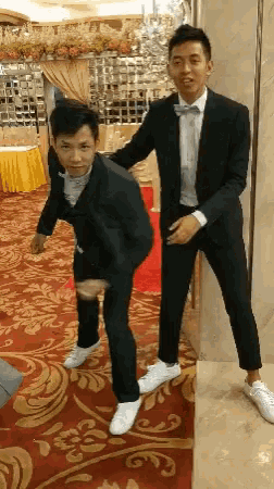 two men in suits and bow ties are posing for a picture