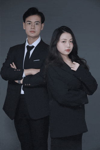 a man and a woman standing next to each other in suits