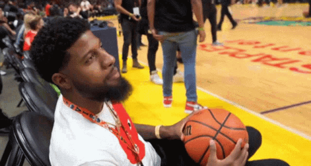 a man holding a wilson basketball on a court