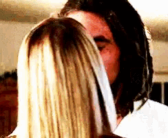 a man and a woman are kissing and the woman is covering the man 's face