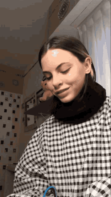 a woman wearing a black and white checkered shirt and a black scarf