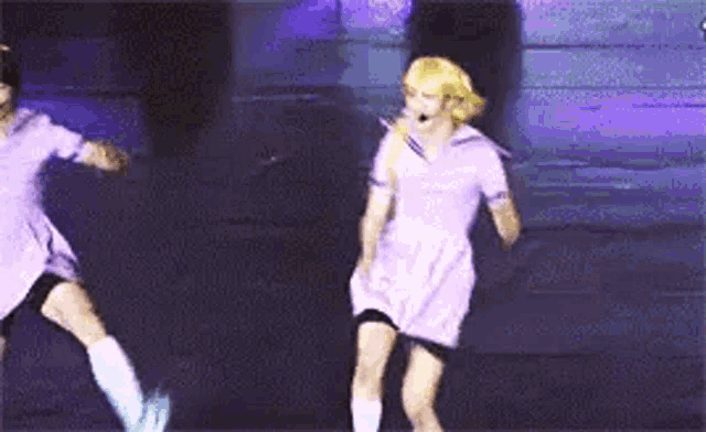 a couple of people are dancing on a stage in purple dresses .
