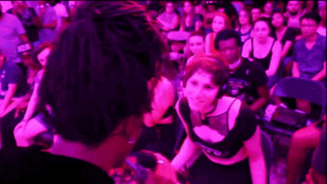 a woman wearing headphones is dancing in a crowd of people