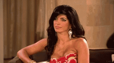 a woman in a strapless dress is sitting on a couch and looking at the camera .