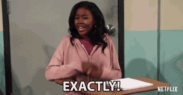 a girl sitting at a desk with the word exactly written on it