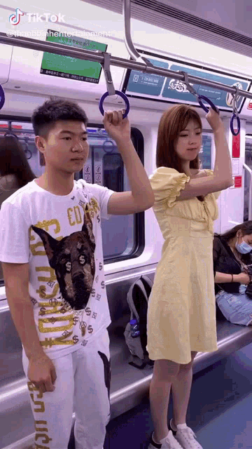 a man and a woman are standing on a subway train holding the handles