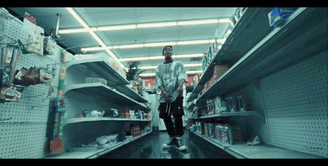 a man stands in a grocery store aisle with empty shelves and a sign that says extreme