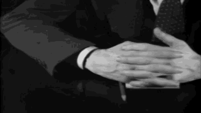 a man in a suit and tie is folding his hands