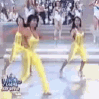 two women in yellow jumpsuits are dancing on a stage .