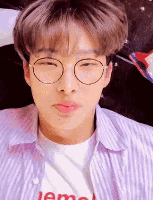 a young man wearing glasses and a striped shirt is making a face .