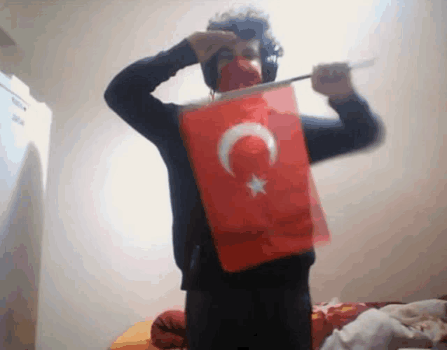 a man wearing headphones holds a red flag with a crescent moon and star