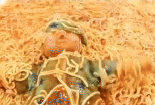 a baby doll is laying on top of a pile of spaghetti noodles .