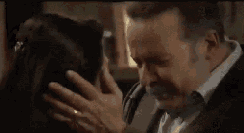 a man and a woman are hugging each other in a room and the man is crying .