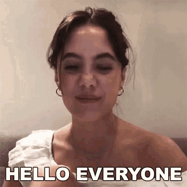 a woman in a white top is saying hello everyone