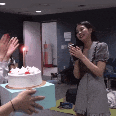 a woman in a gray dress is holding a cake in front of her